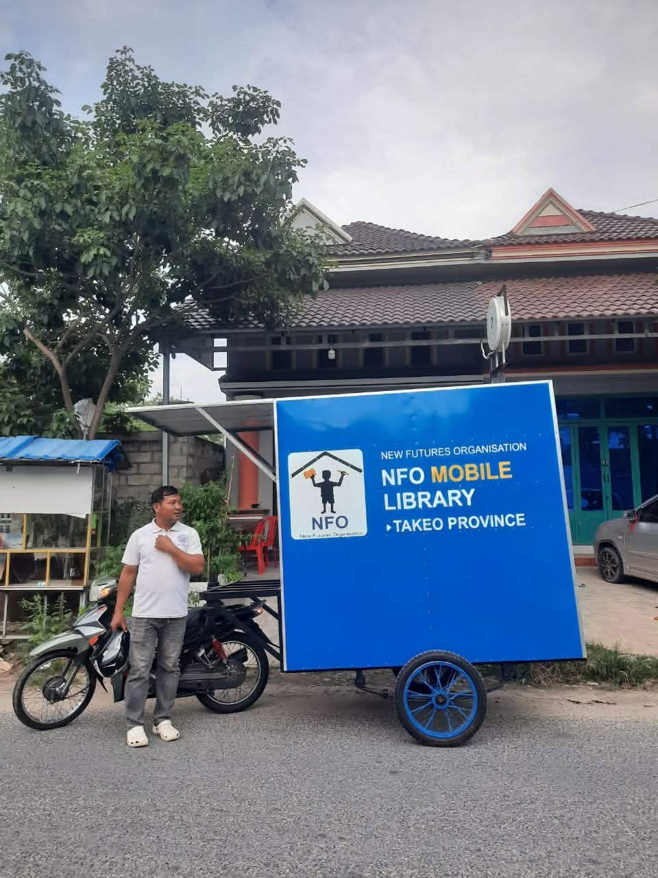 An NFO staff member with the Mobile Library trailer and motorbike