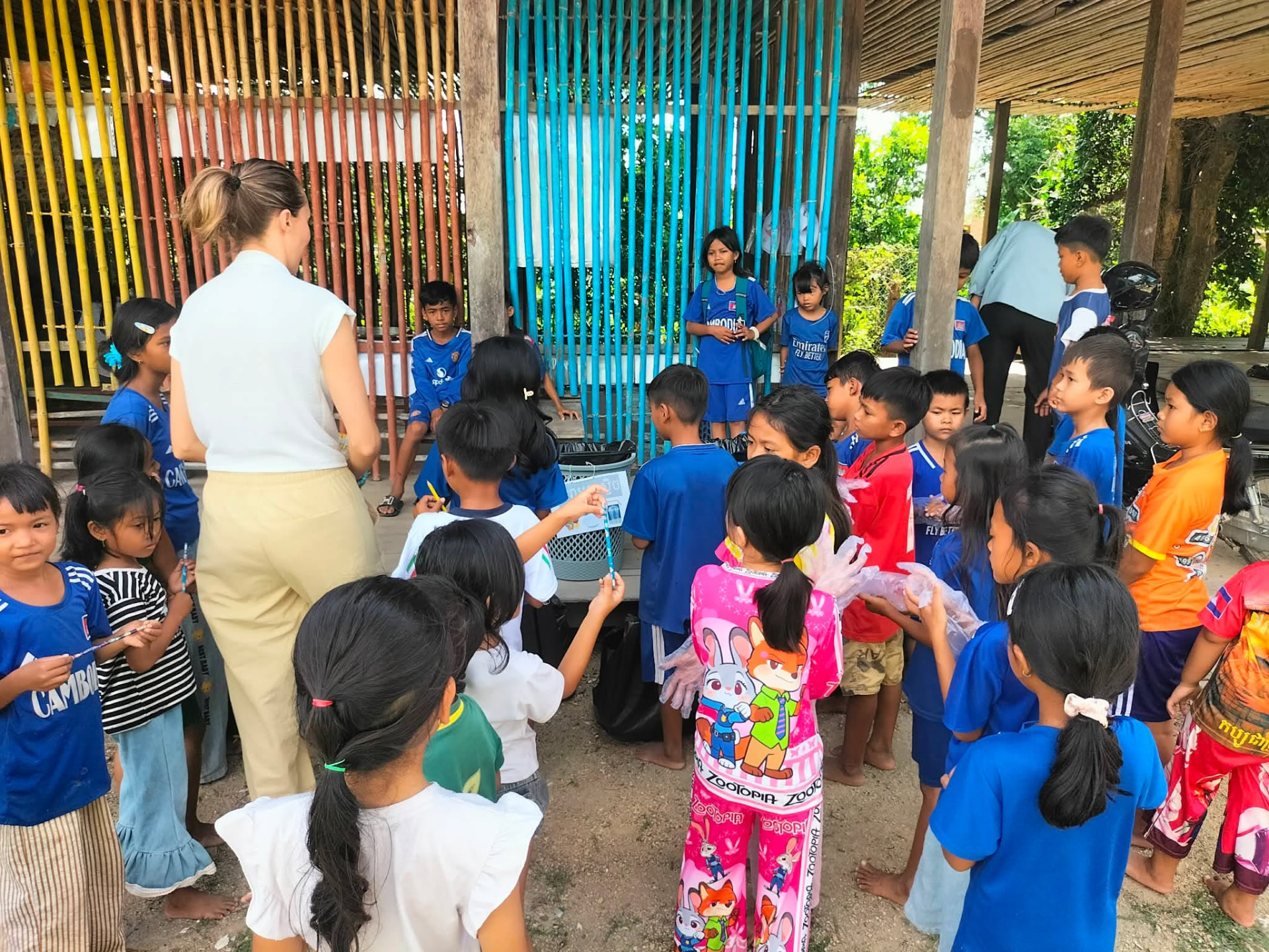 A volunteer leads a recycling awareness session with pupils in the school yard